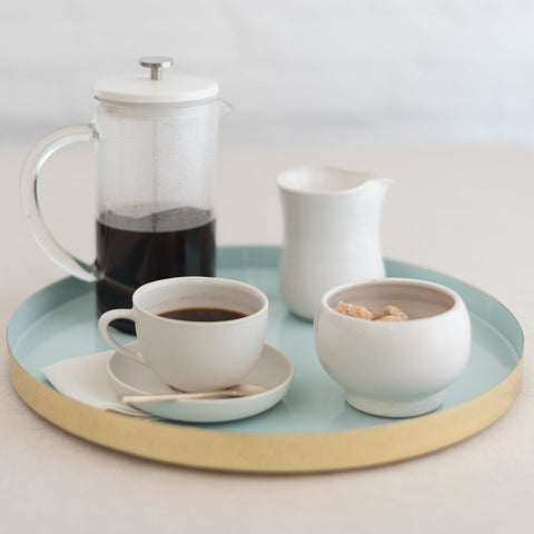 A tray with a french press, coffee cup, and bowl of sugar cubes.