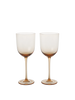 A selection of elegant, mouth-blown glassware including wine glasses, cocktail glasses, and liqueur glasses, displayed on a table. The glassware comes in clear and various colored tints.