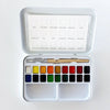 An open metal watercolor paint palette with 18 color wells, a wooden-handled brush, and a printed color chart inside the lid, shown on a white background.