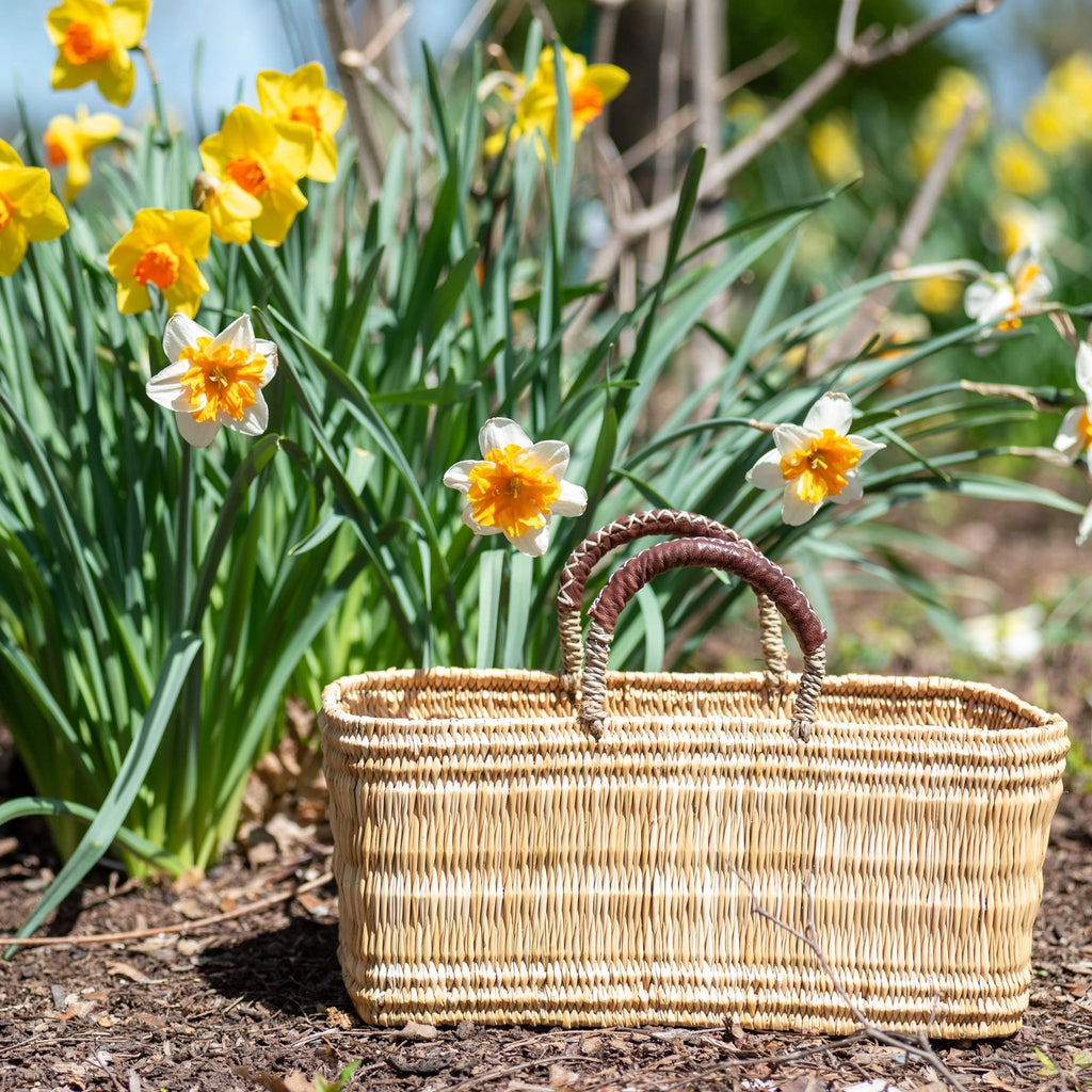 Woven basket on the ground with yellow flowers in the background