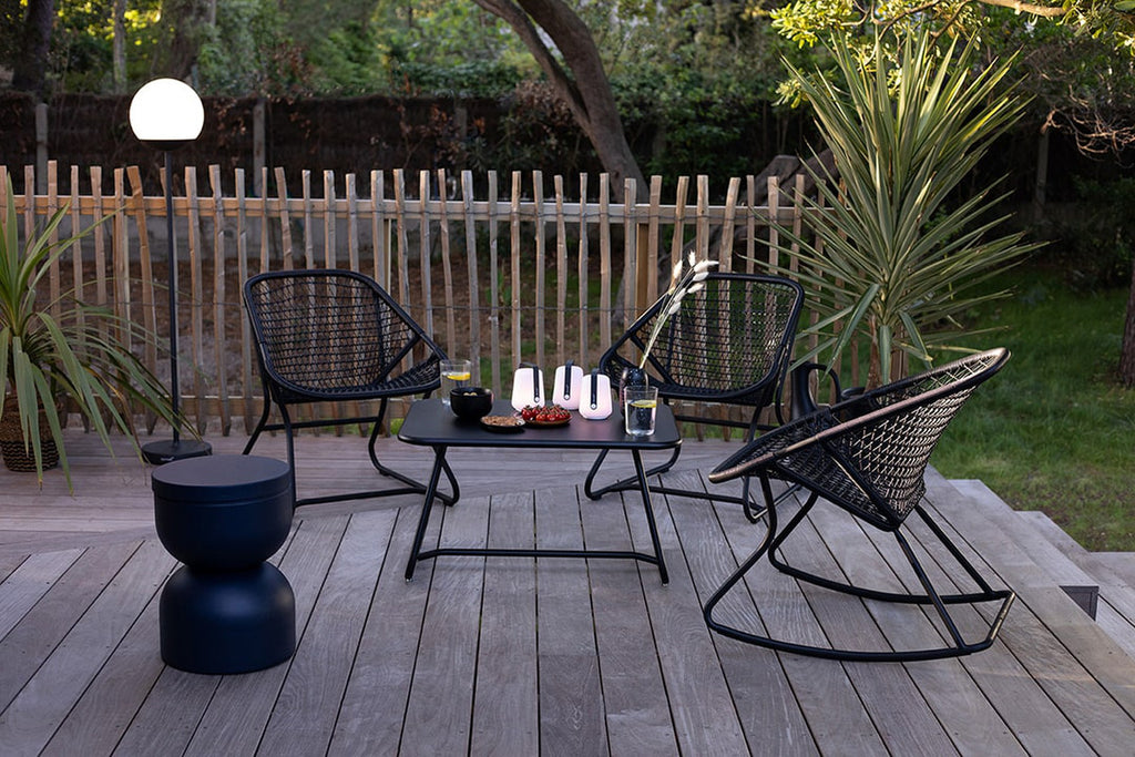 Three black outdoor rocking chairs and table.