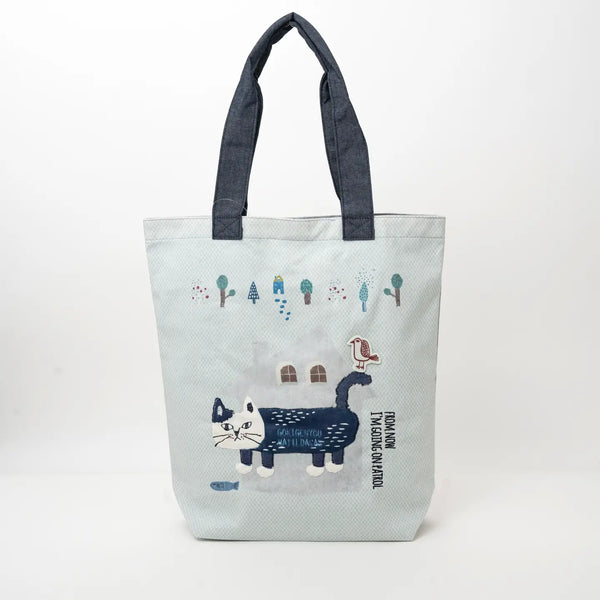 A light blue canvas tote bag with dark navy blue fabric handles, featuring a whimsical winter cat illustration on a clean white background.