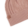 Blush pink knitted beanie with cable pattern and brand label on a white background