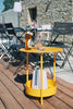 A honey yellow Salsa Side Table with a steel frame, a steel sheet table top, and a steel mesh bottom.