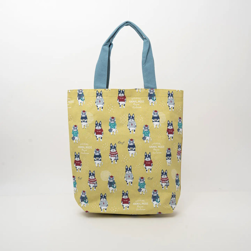A yellow tote bag with a repeating pattern of French Bulldog characters wearing colorful sweaters, featuring light blue handles, set against a plain white background.