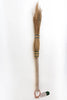A miniature hand-woven straw broom with a light wood handle and blue wrapping bands, shown against a plain white background with a small tag attached.