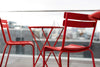 Two red Luxembourg side chairs with tubular aluminum frame and curved aluminum slats.