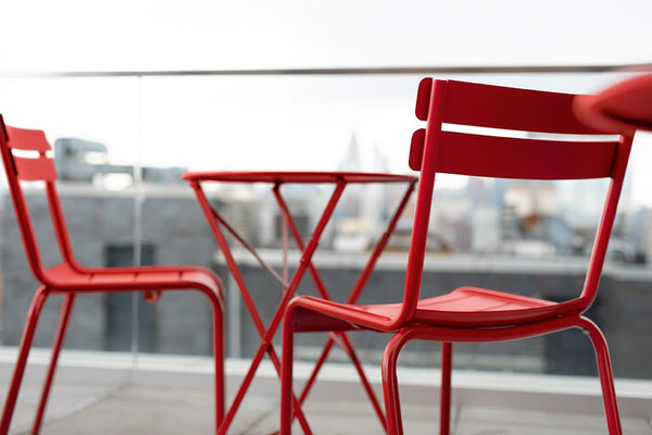 Two red Luxembourg side chairs with tubular aluminum frame and curved aluminum slats.