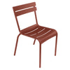 One red Luxembourg side chair with tubular aluminum frame and curved aluminum slats.