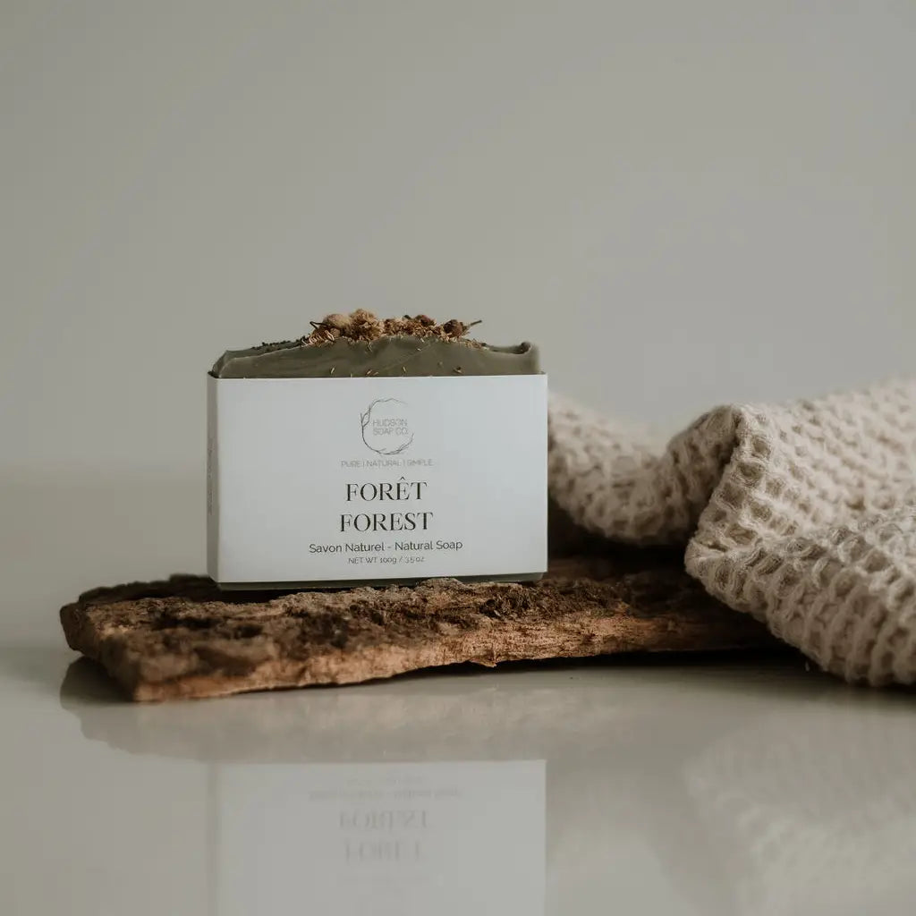A bar of natural soap with placed on a wooden surface with decorative elements around it.