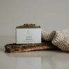 A bar of natural soap with placed on a wooden surface with decorative elements around it.