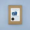 A kraft paper box package labeled 'cyanotype kit capture the postcard' with blue indigo-style postcard designs and a circular 'PAR' seal, centered on a light blue background.