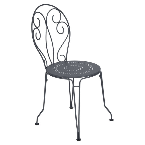 Black outdoor metal chair with hand-forged scrollwork and perforated seat. 