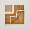 A folded scarf with a geometric stripe pattern in mushroom, rich tan, and clotted cream colors, displaying the Lorna Murray brand name.