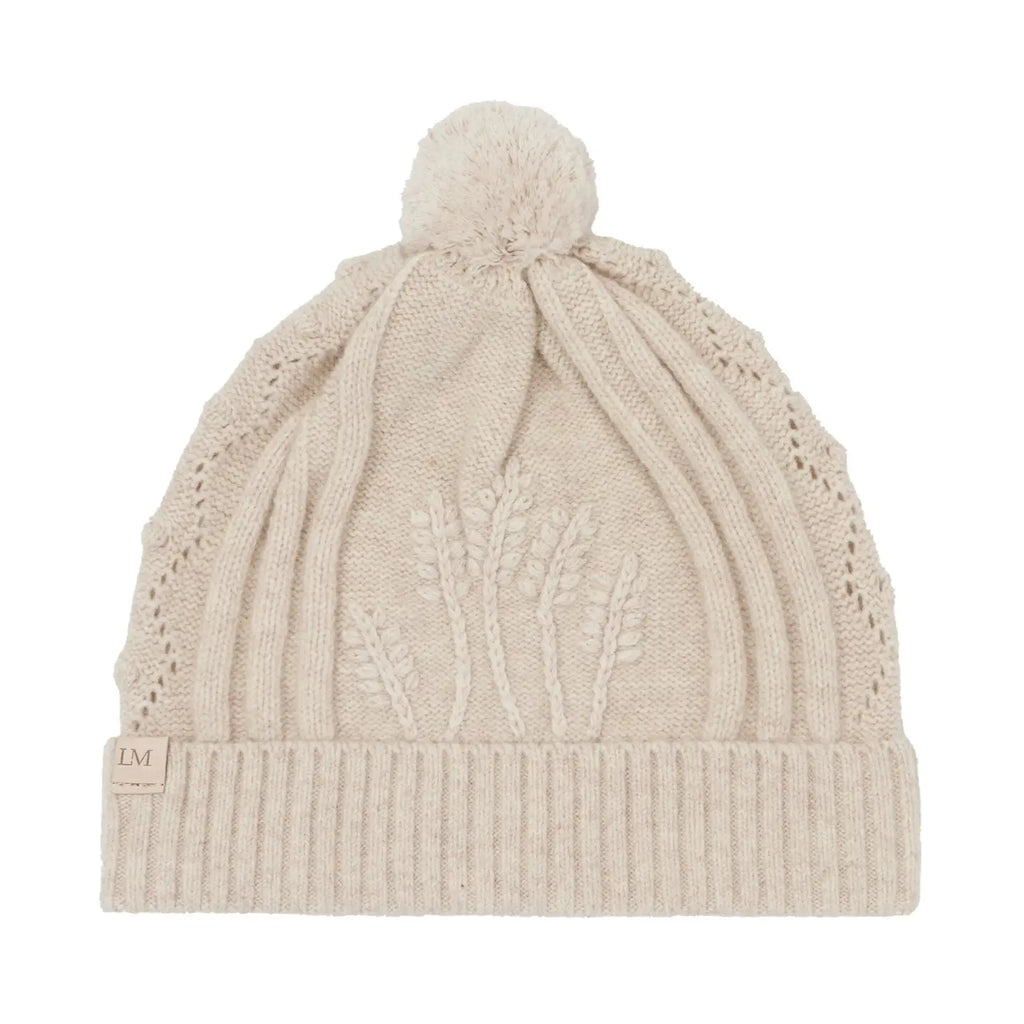 Beige knit beanie with a pom-pom on a white background