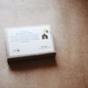 A boxed of oilbased sticks by Smilogy, featuring a white paper label with product details and illustrations, resting on a textured brown kraft paper background.