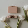 A bar of natural soap placed on a wooden surface with decorative elements around it. White tulips laying around the soap