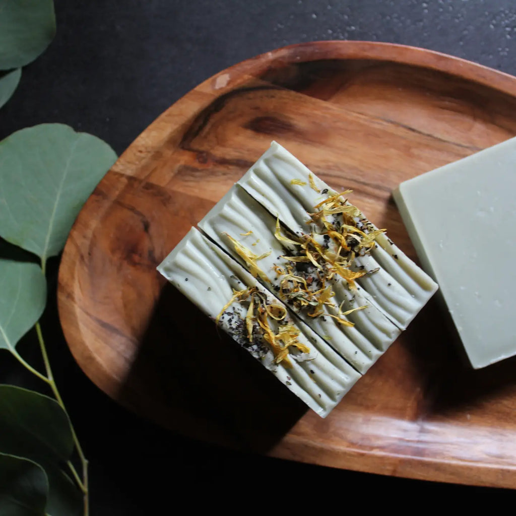 A bar of natural soap placed on a wooden surface with decorative elements around it.