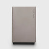 A minimalist hardcover notebook or journal in a muted taupe-gray color, featuring small black text printed vertically on the right side of the cover, set against a clean white background.