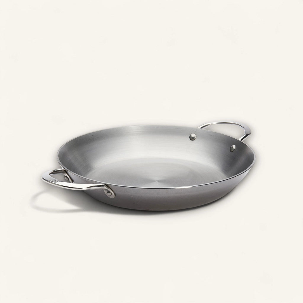 Stainless steel paella pan on a white background