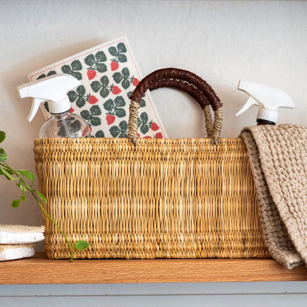 Wicker basket with cleaning supplies on a wooden surface