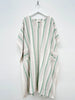 Striped kaftan with green and white pattern on a hanger against a white background