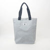 A light gray textured canvas tote bag with dark gray fabric handles and a small white brand label on the front, photographed against a plain white background.