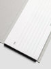 Close-up of a notebook with lined pages on a light gray background