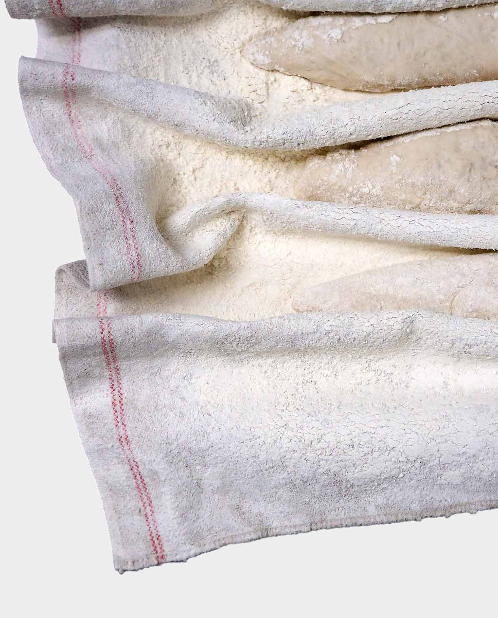 Close-up of a white fabric with red stitching on a light gray background