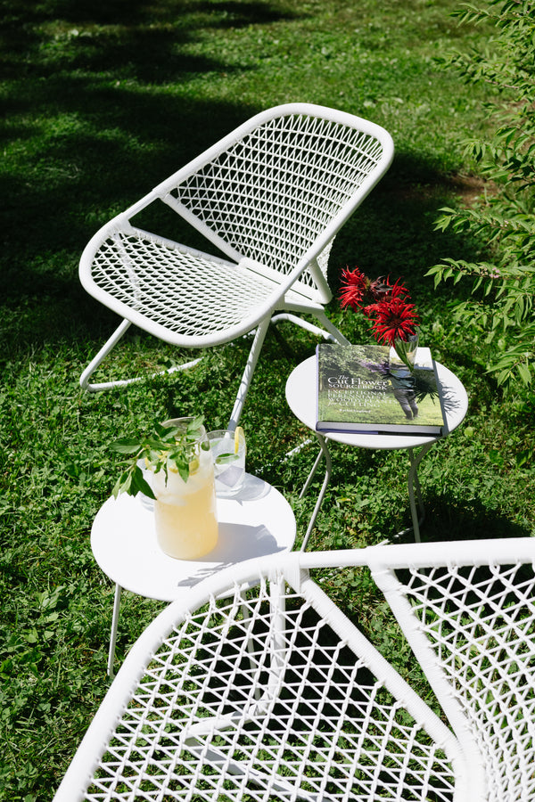 White outdoor furniture set with a table and chairs on grass.