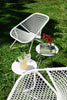 White outdoor furniture set with a table and chairs on grass.