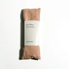 Blush colored eye pillow with packaging on a white background