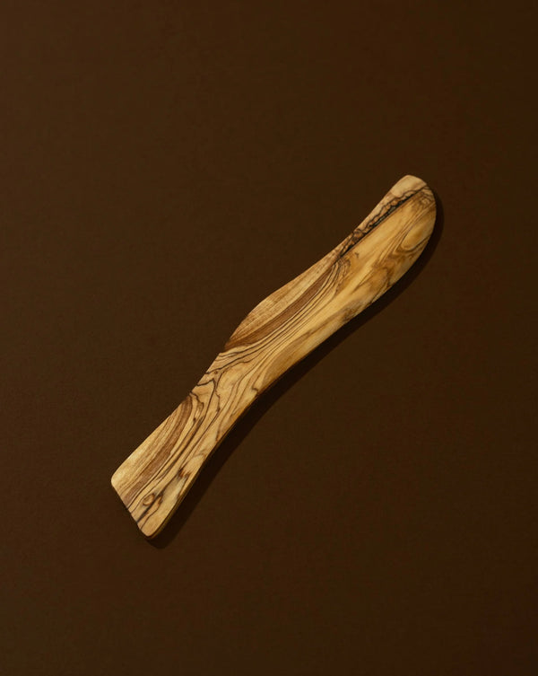 Wooden spatula with olive wood pattern on a brown background