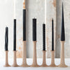 A selection of black taper candles arranged by design, with natural and twisted patterns, made from beeswax, displayed on candle holders.