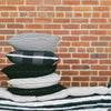 Five stacked solid and striped pillows.