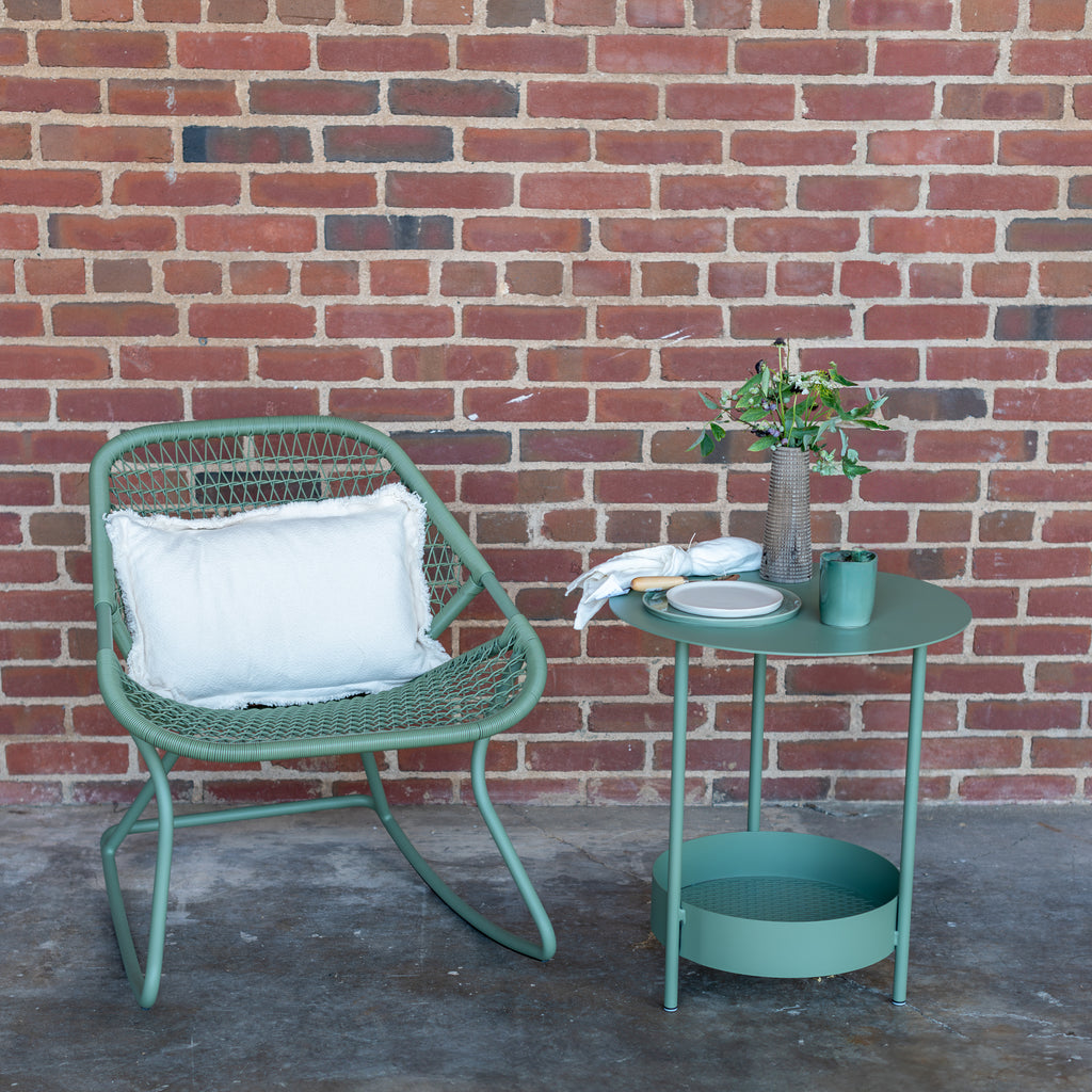 Green outdoor rocking chair with green side table. 