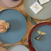 Round serving trays in various colors on a wooden table.