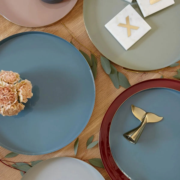 Round serving trays in various colors on a wooden table.