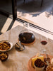 One polished stainless steel coaster with a shallow lip and central anti-slip pad, displayed on a marble table.