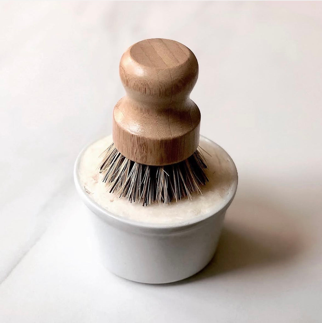 Dishwashing brush with wooden handle and white base on a light background