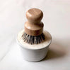 Dishwashing brush with wooden handle and white base on a light background