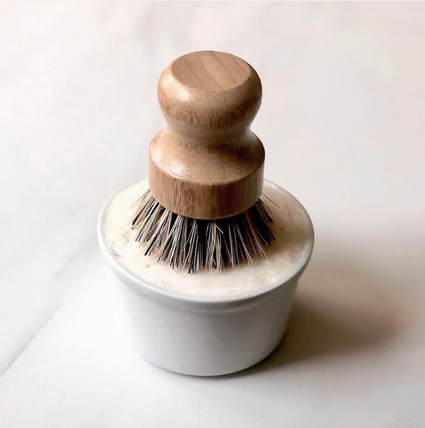 Dishwashing brush with wooden handle and white base on a light background