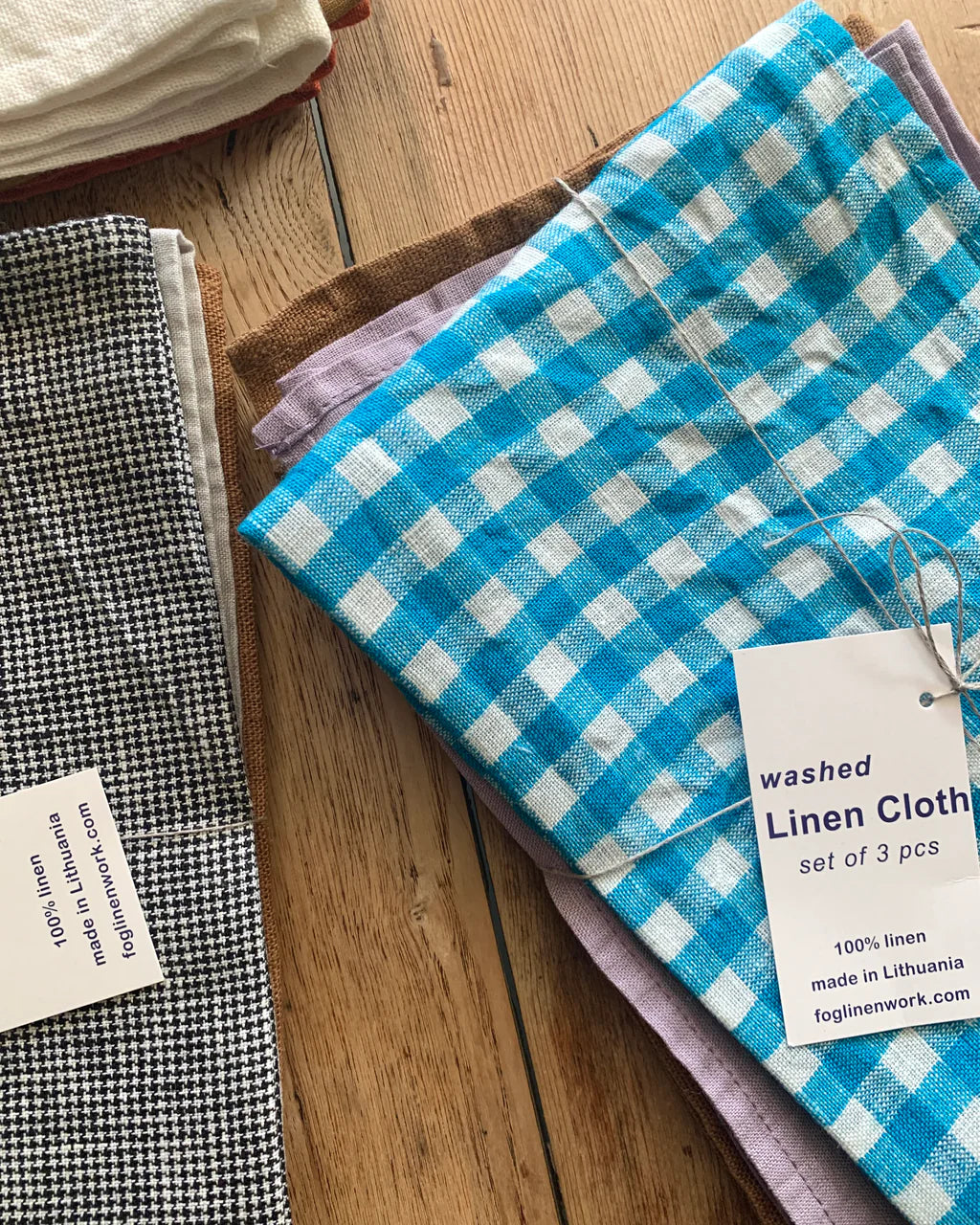 Set of washed linen cloths with tags on a wooden surface