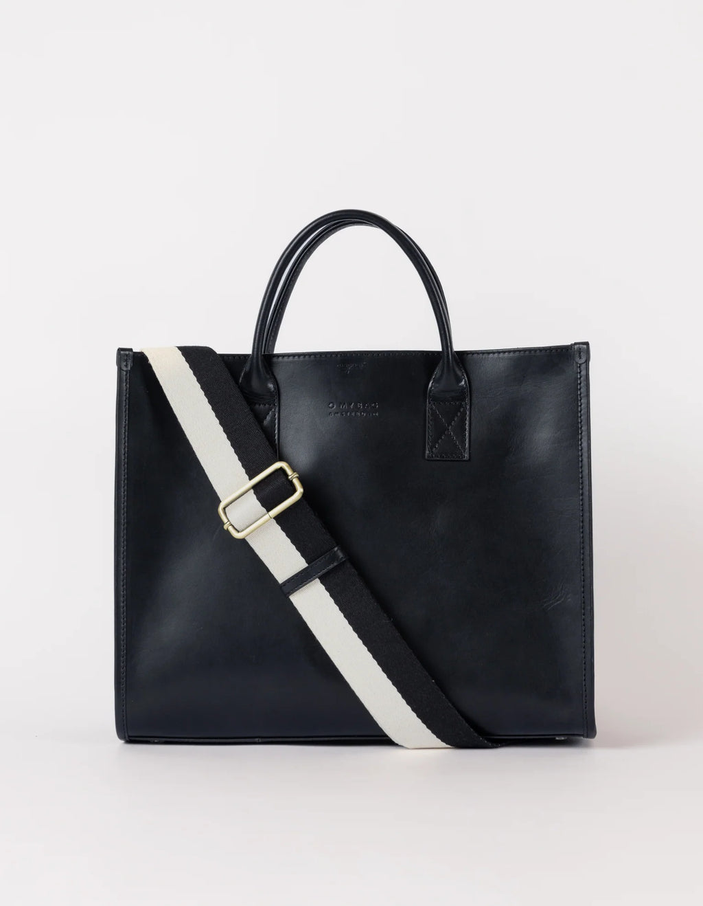 A black leather tote bag with a structured silhouette, featuring a white and red adjustable strap, two handles, and a minimalist latch closure.