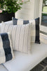A set of striped throw pillows with a geometric pattern, predominantly in blue and white colors, displayed on a neutral surface.