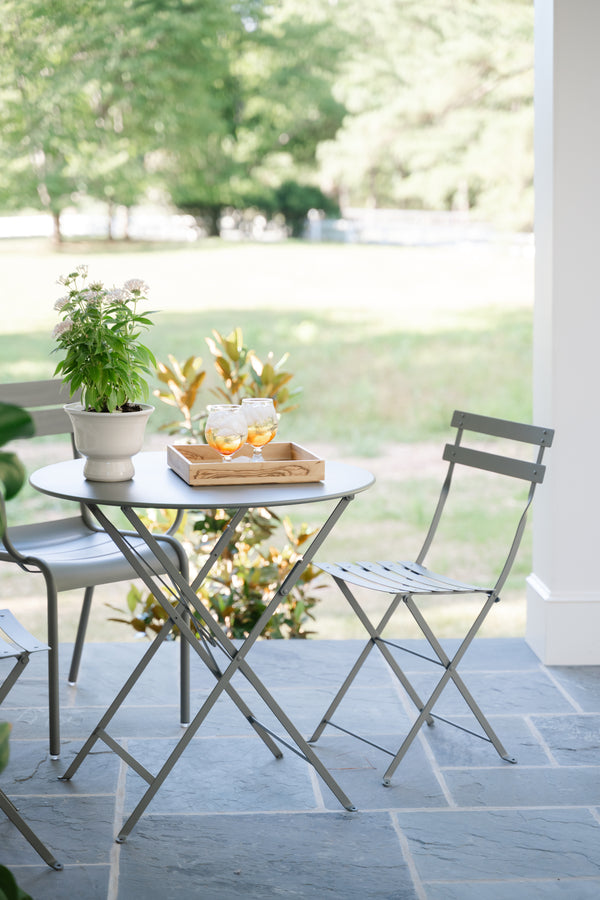 A gray Bistro metal chair and table set on an outdoor patio.