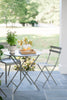 A gray Bistro metal chair and table set on an outdoor patio.