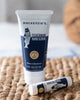 Mackenzie's Fisherman Hand Scrub tube and Knuckle Wax stick on a woven surface