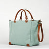 A menthe seafoam cotton tote bag with brown leather handles and a removable brown leather strap, featuring a zippered closure and an interior pocket, set against a white background.