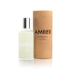 A bottle of 'Amber' eau de toilette with a clear glass container and a silver cap, next to its cylindrical brown cardboard packaging with the word 'AMBER' printed on it.